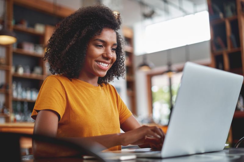 black woman in yellow shirt looking at her laptop - How to Improve and Maintain your Email Deliverability