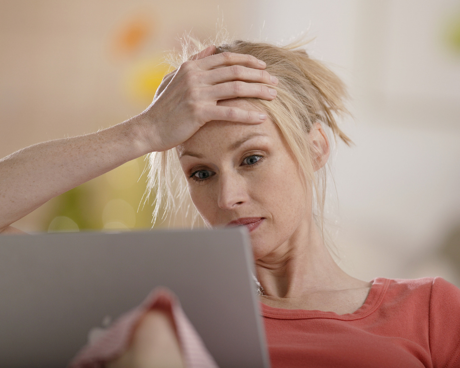 A woman sitting on a couch looking at a laptop, frustrated with Mailchimp emails going to spam.