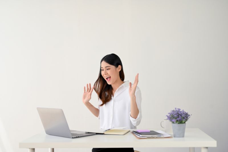 Woman looking happy while using a laptop at her desk