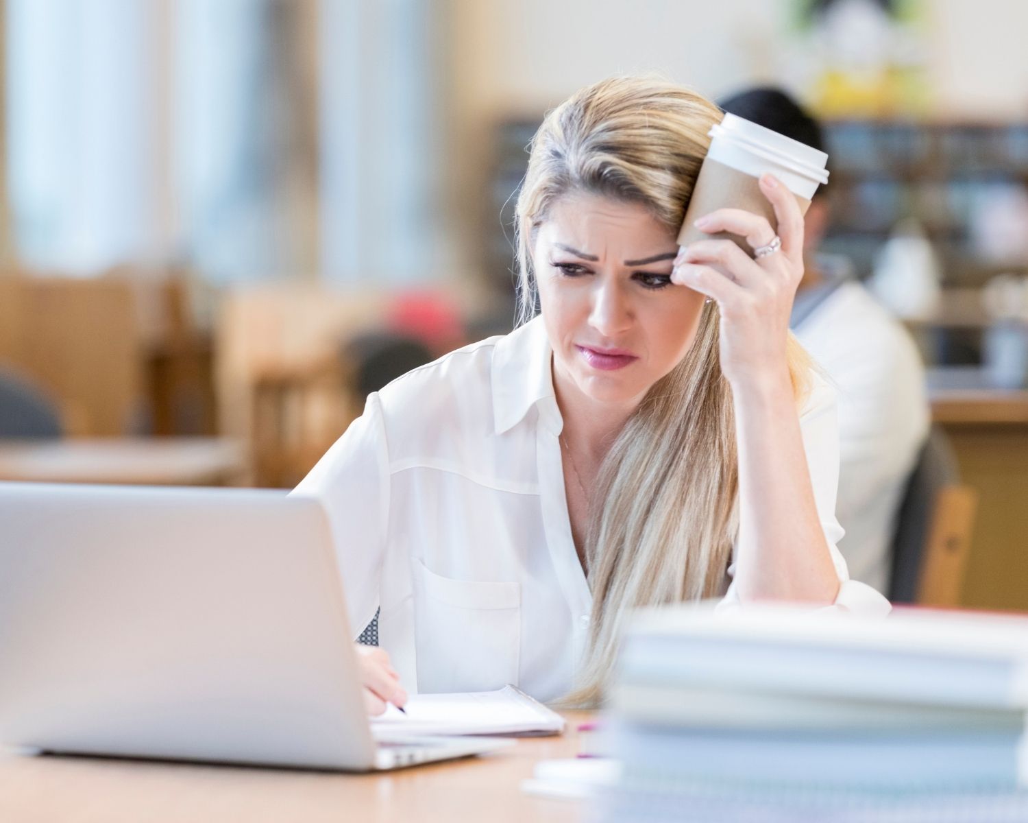 A woman fixing her laptop in a library - SendGrid Emails Going to Spam