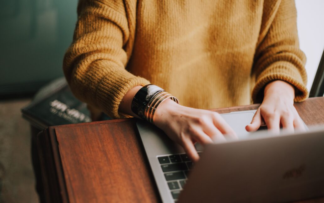 woman at desk typing on laptop