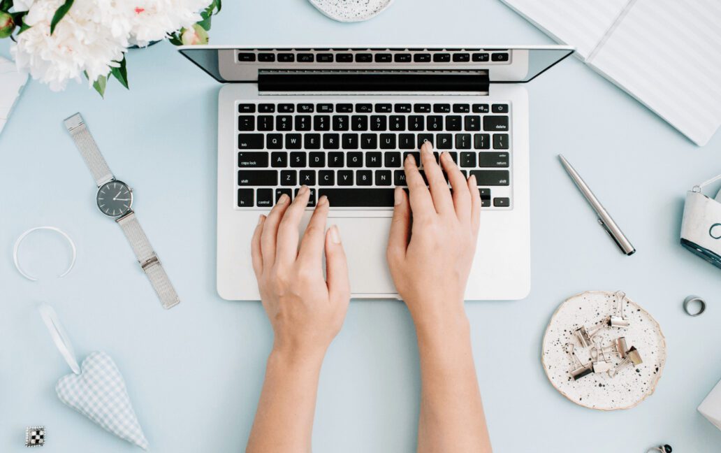 two hands typing on laptop