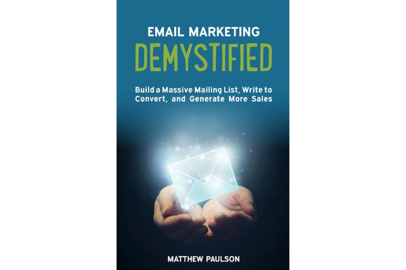 Book cover of "Email Marketing Demystified" by Matthew Paulson, one of the best books on email marketing, featuring hands holding a glowing envelope with blue background and white and green text.