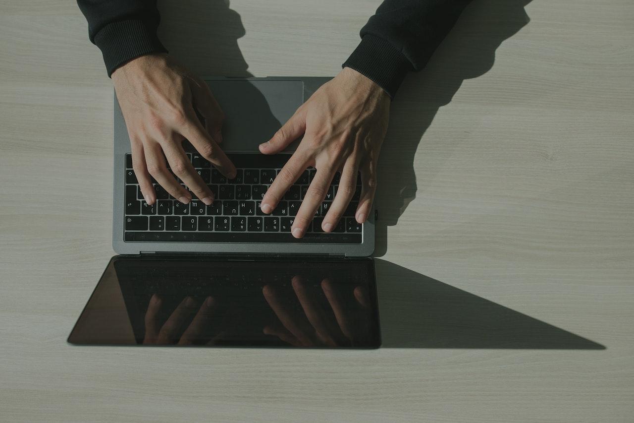 A person's hands typing on a laptop computer.