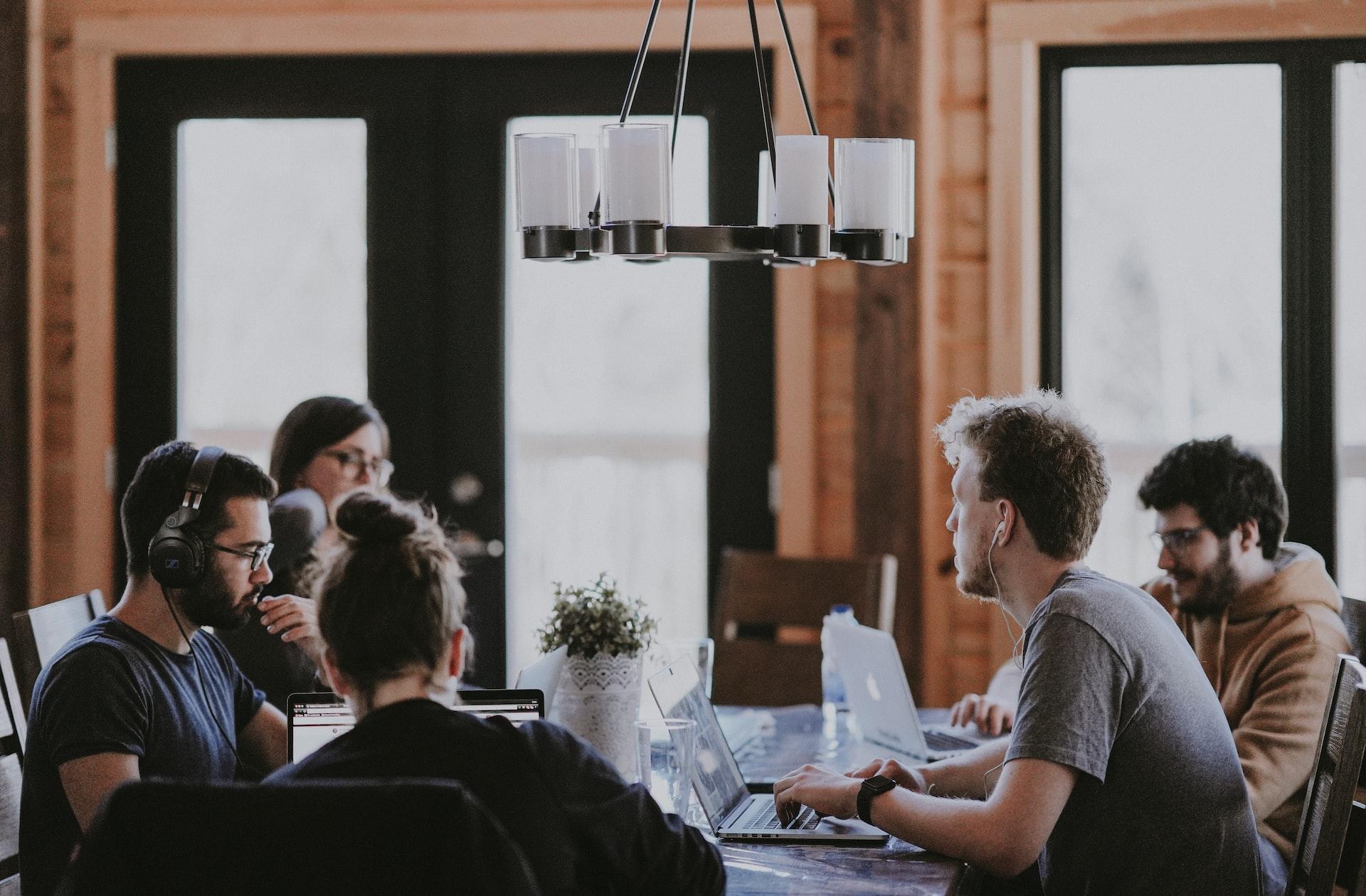 A group of people sitting at a table with laptops.