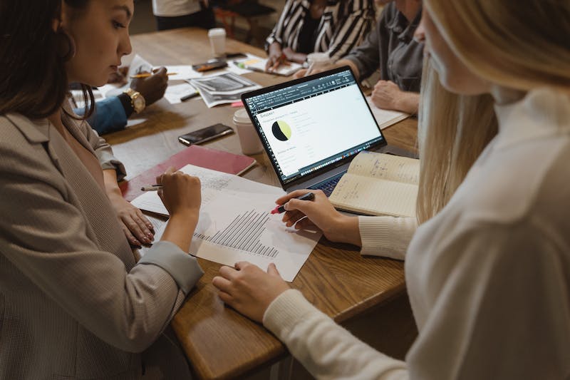 A group of people sitting around a table and working on a laptop.