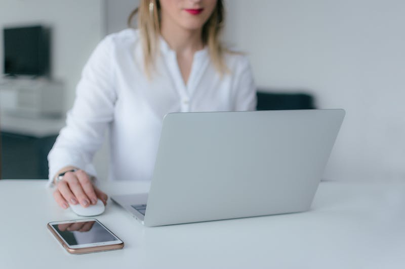 A woman sitting at a desk with a laptop and cell phone.