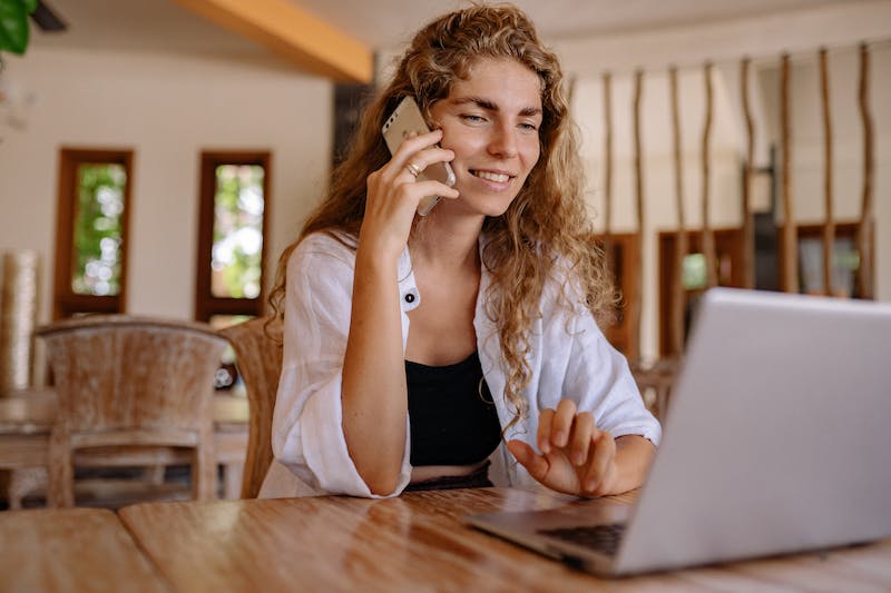 Woman talking on her phone while working on a laptop.