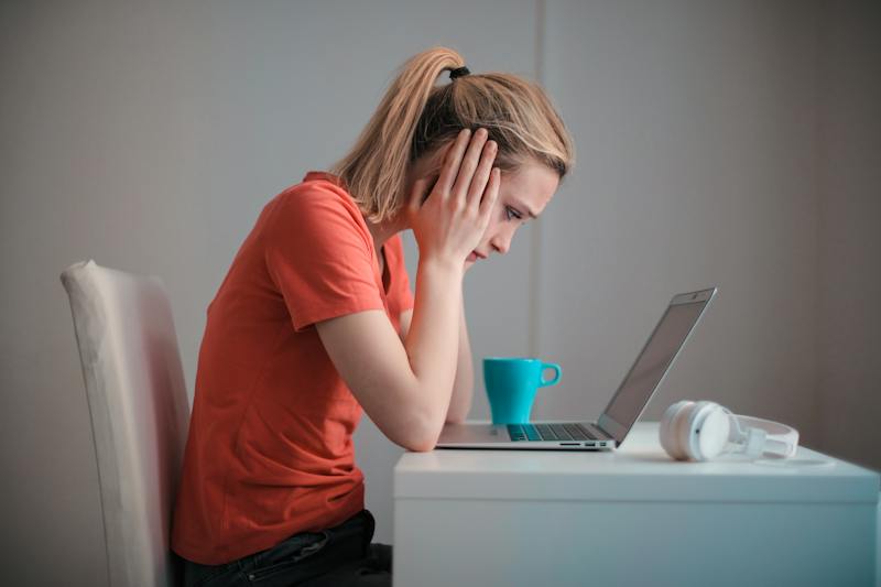 Woman looking worried sitting in front of a laptop