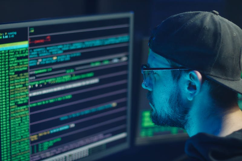 Man in front of a computer showing difficult to read data.