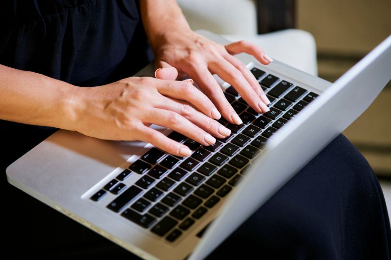 Woman typing on a laptop, possibly composing an email 