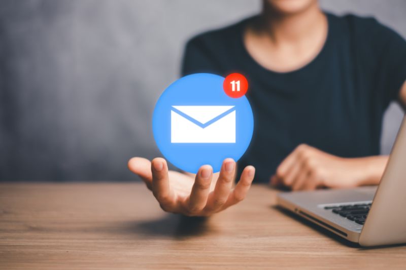 Vista em close-up de um homem segurando um ícone de envelope de e-mail enquanto trabalha em seu laptop