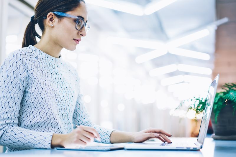 Woman using a laptop, focused on implementing a DMARC reject policy.