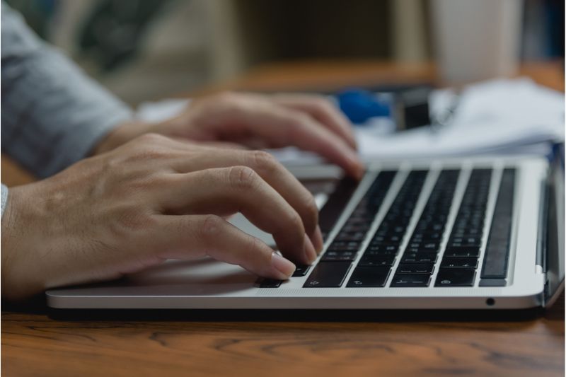 Close-up of a person's hands typing a newsletter on a laptop