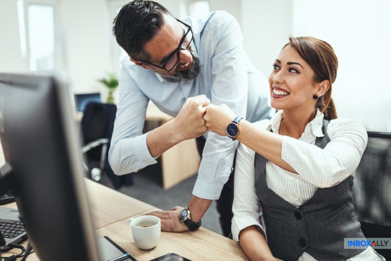 Colegas felizes batendo os punhos em uma mesa, simbolizando a resolução bem-sucedida de problemas com e-mails enviados, mas não recebidos pelo destinatário