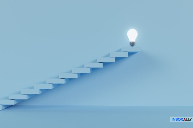 A light bulb casts a glow at the top of a blue staircase against a serene blue background, reminiscent of navigating obstacles like Yahoo blocking my emails.