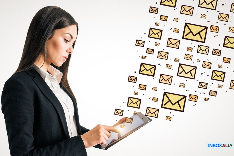 Professional woman in a suit using a tablet, surrounded by a stream of email icons, symbolising the overwhelming flow of emails