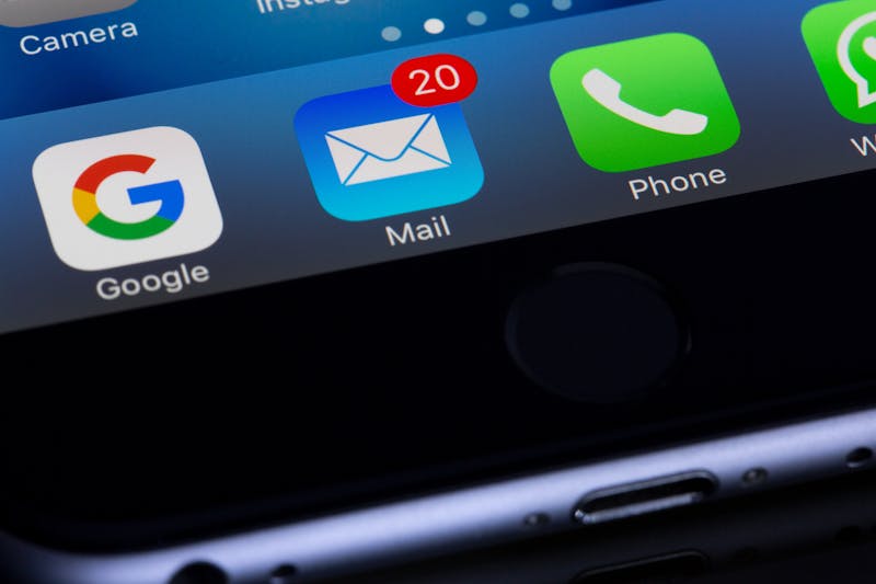 O close-up da tela de um smartphone revela ícones de aplicativos para Google, Mail com 20 notificações não lidas lotando a caixa de entrada, Telefone e WhatsApp.