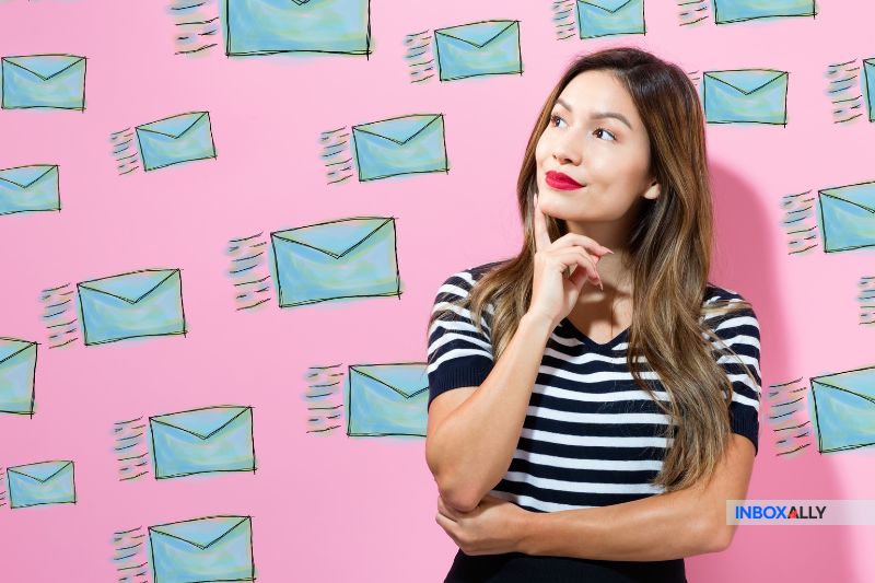 A woman stands against a pink background adorned with illustrated envelopes, pondering the impacts of email metadata on deliverability.