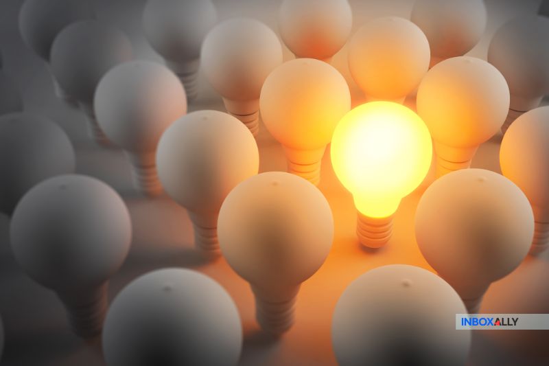 Amidst a cluster of unlit light bulbs, one glowing bulb shines brightly at the center, symbolizing impact and standing out much like how excellent email deliverability ensures your message doesn't get lost in the vast sea of unread messages.