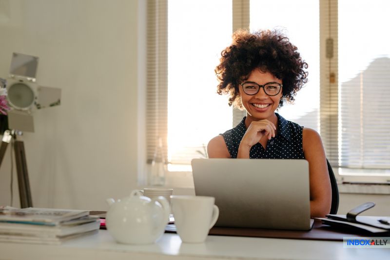 A person sits at a desk with a laptop, smiling as they explore email metadata. 