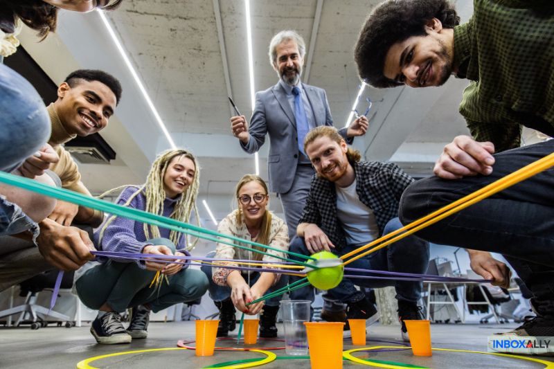A group of subscribers engages in a team-building activity, creatively using strings to maneuver a ball into a cup, strengthening cooperation and unity.