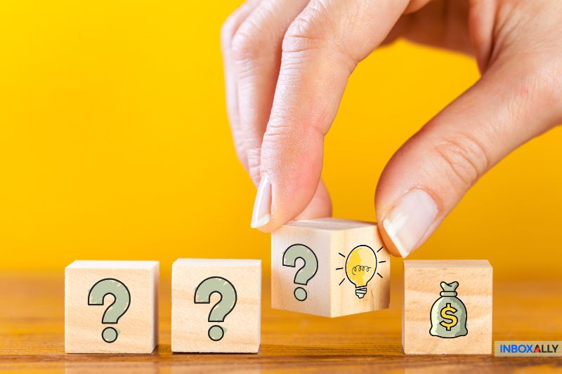 A hand picks up a wooden block with a light bulb icon, symbolizing bright ideas for Email Lead Generation. Other blocks display question marks and a money bag symbol against a yellow background.