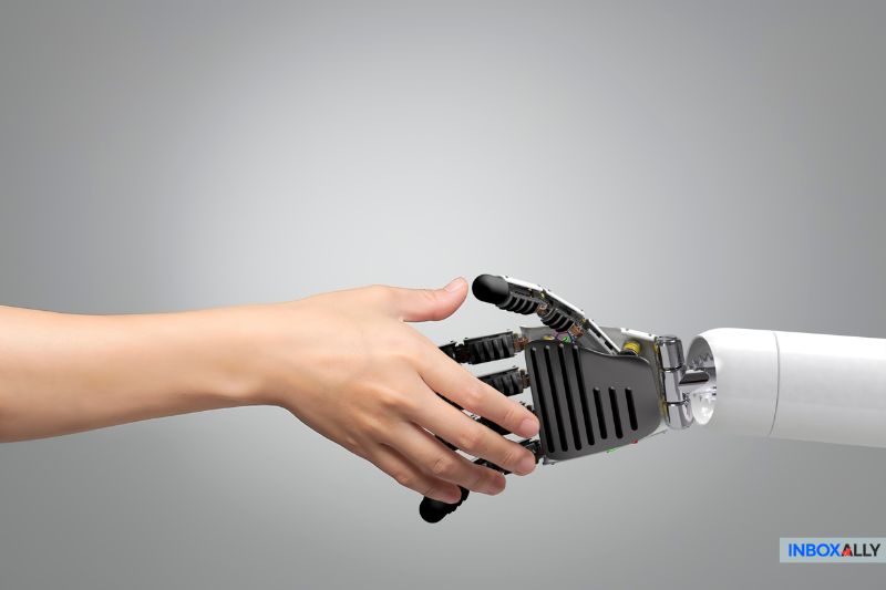 A human hand reaches out in a gesture of connection with a robotic arm, symbolizing the future of human marketing, against a gray background.