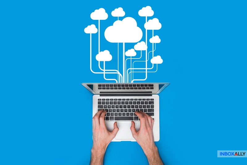 Hands typing on a laptop with cloud icons above, representing cloud computing or data storage on a blue background. This illustrates the seamless integration of hosted email spam filters, enhancing digital security in an ever-evolving online landscape.