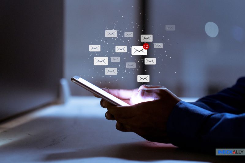 Pessoa segurando um smartphone com ícones de e-mail digital e uma notificação de 12 novas mensagens, destacando a entrega segura com o Mimecast SMTP Relay acima da tela.