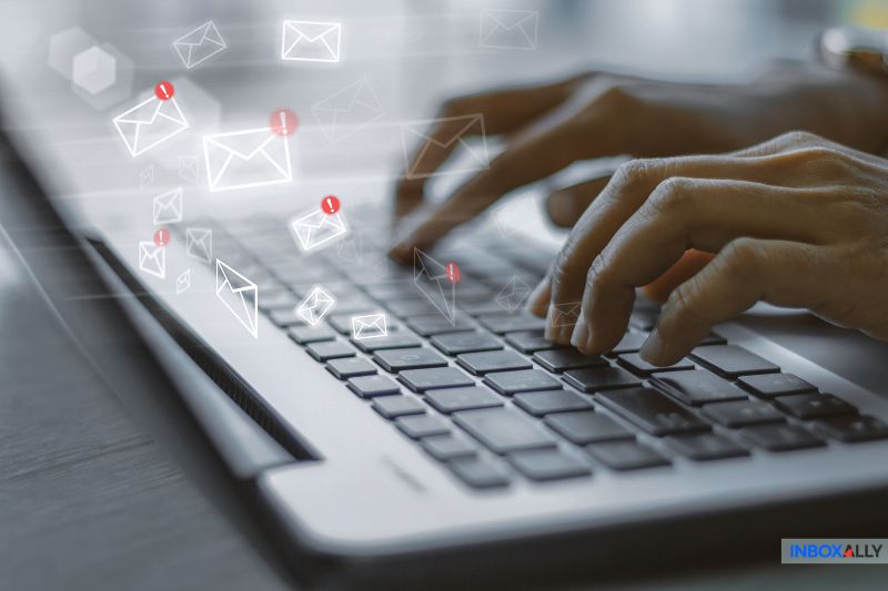 Manos escribiendo en un teclado de ordenador portátil con iconos digitales de correo electrónico y alertas de notificación, destacando el uso de un Servicio de Correo Electrónico como Mailgun o Amazon SES encima de las teclas.